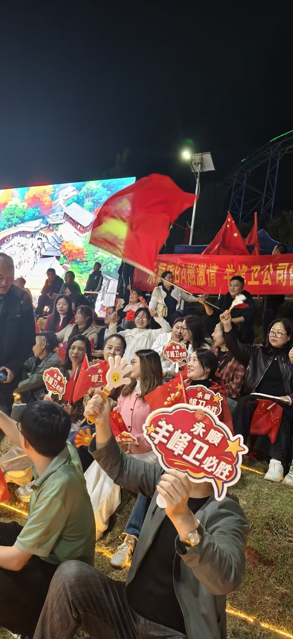 夜里灯从球场四角打下来，前两排照得清楚，后面的就是黑的山影